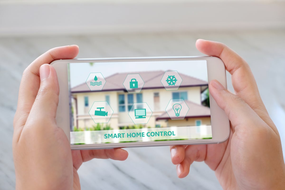 Hand using smart phone as smart home control application, smart home concept, technology and lifestyle